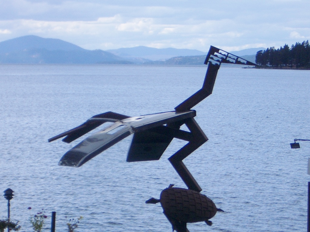 photo of welded sculpture of a heron, with a mountain lake in the background